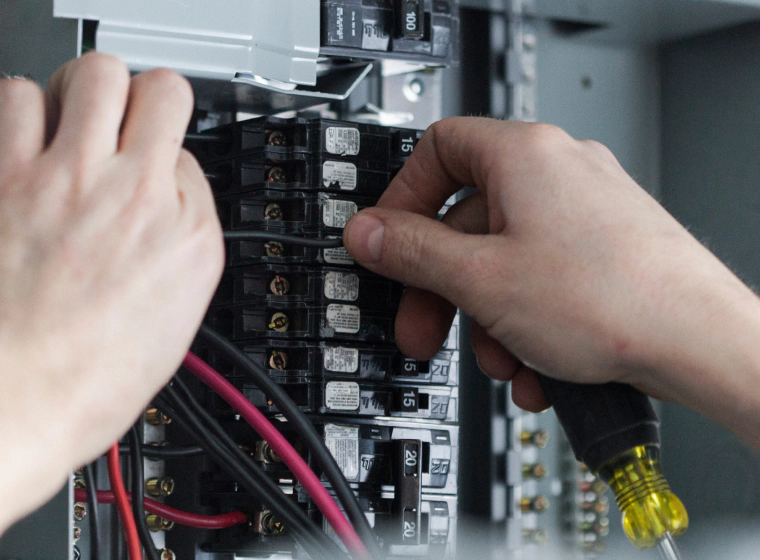 worker checking some electrical panels on a grey box of a house