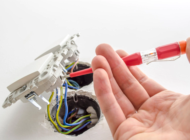 worker installing a new white switch on a white wall