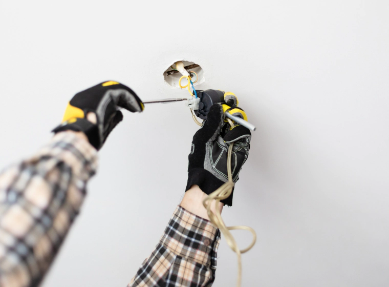 worker with black and yellow gloves installing some lights on a new house